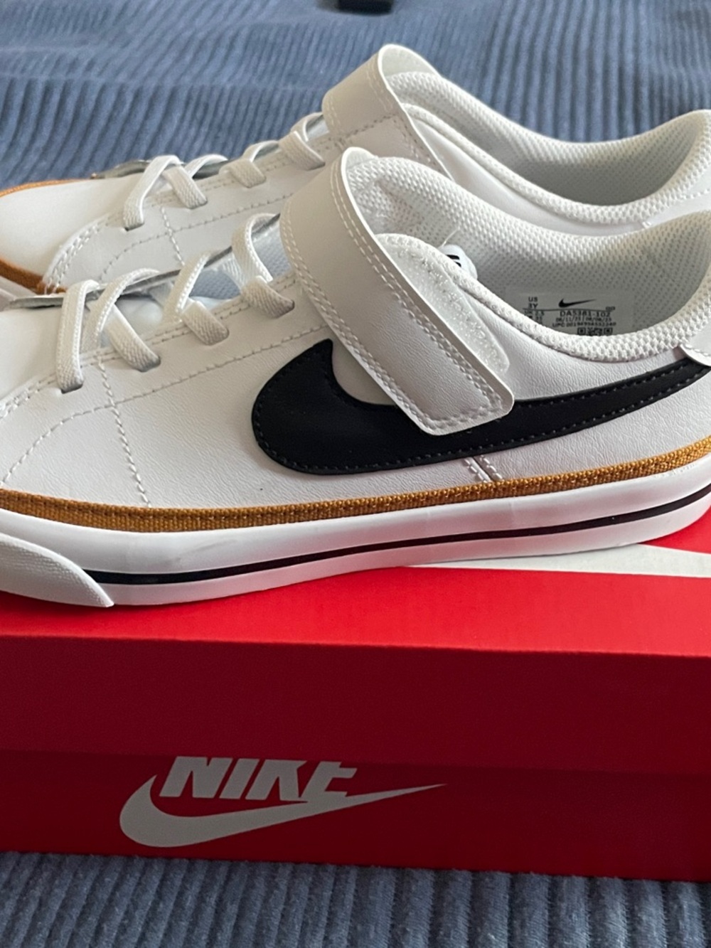 Nike Kids White Sneakers with Black Swoosh and Gold Accent